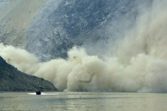 2008年5月19日，一辆运送物资的冲锋舟从映秀镇返回都江堰，在经过狗脚湾峡谷时，突然遭遇山体塌方，山上滚落的巨石在峡谷中溅起浓浓烟尘。冲锋舟正逃出生天。